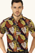 A man wearing a multicolored shirt with a monstera leaf pattern.